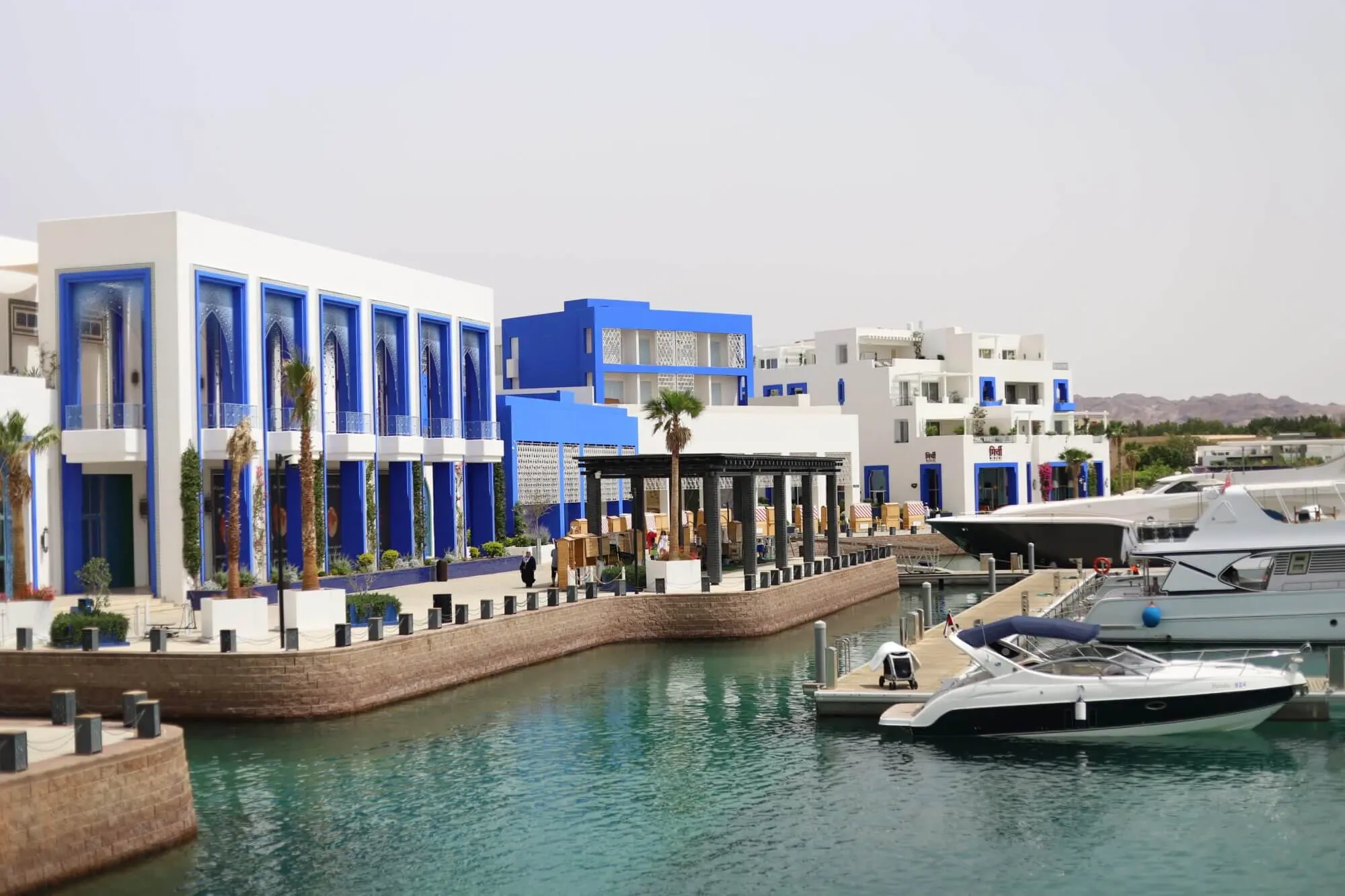 Boats moored beside the blue and white waterfront buildings of Ayla Marina
